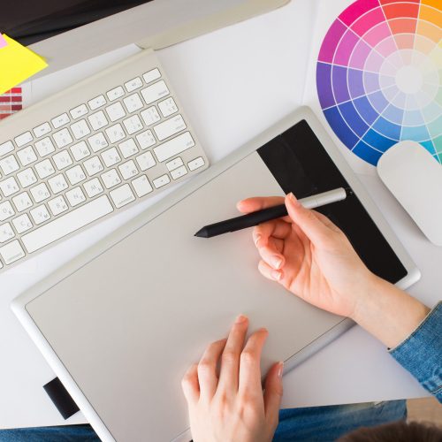 Young pretty Graphic designer using graphics tablet to do her work at desk